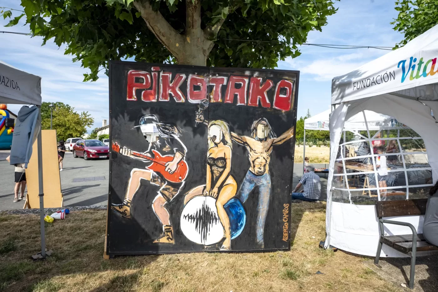 Panel ilustrado de Pikotako junto a los puestos del recinto